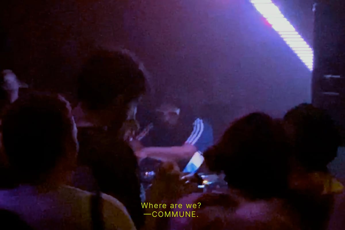 A dimly-lit club. People gathered around a DJ booth, bathed in violet light. Subtitled text reads: “Where are we? — COMMUNE.